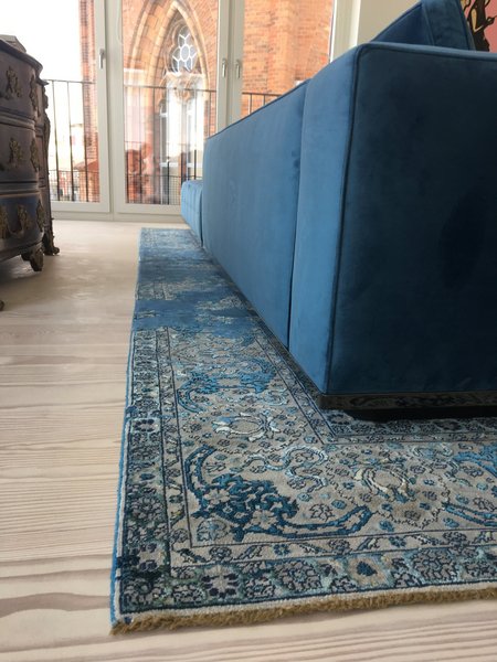 Auffälliger Teppich in Blautönen unter blauem Sofa im Wohnzimmer 